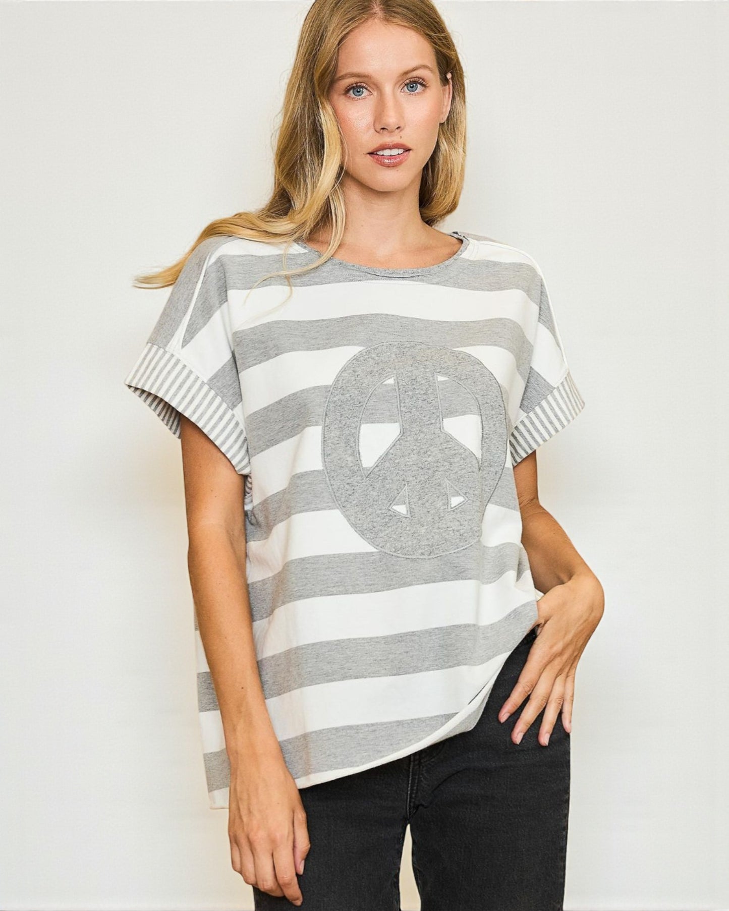 Woman wearing a gray and white striped sweater with a large circular design on a plain background