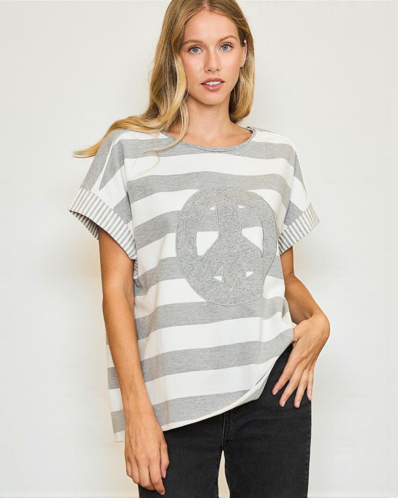 Woman wearing a gray and white striped sweater with a large circular design on a plain background