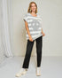 Woman wearing a gray and white striped sweater and black pants in a studio setting