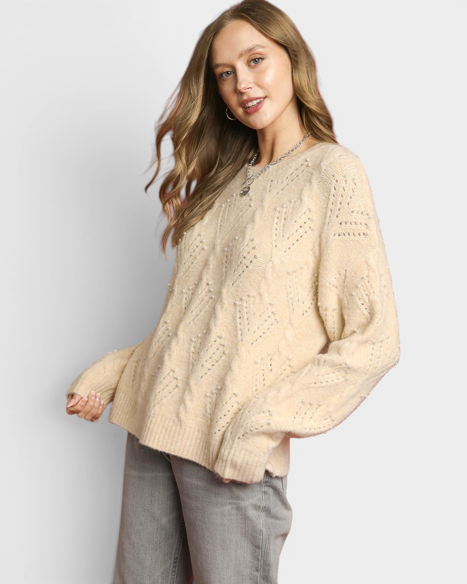 Woman wearing a beige sweater against a plain background