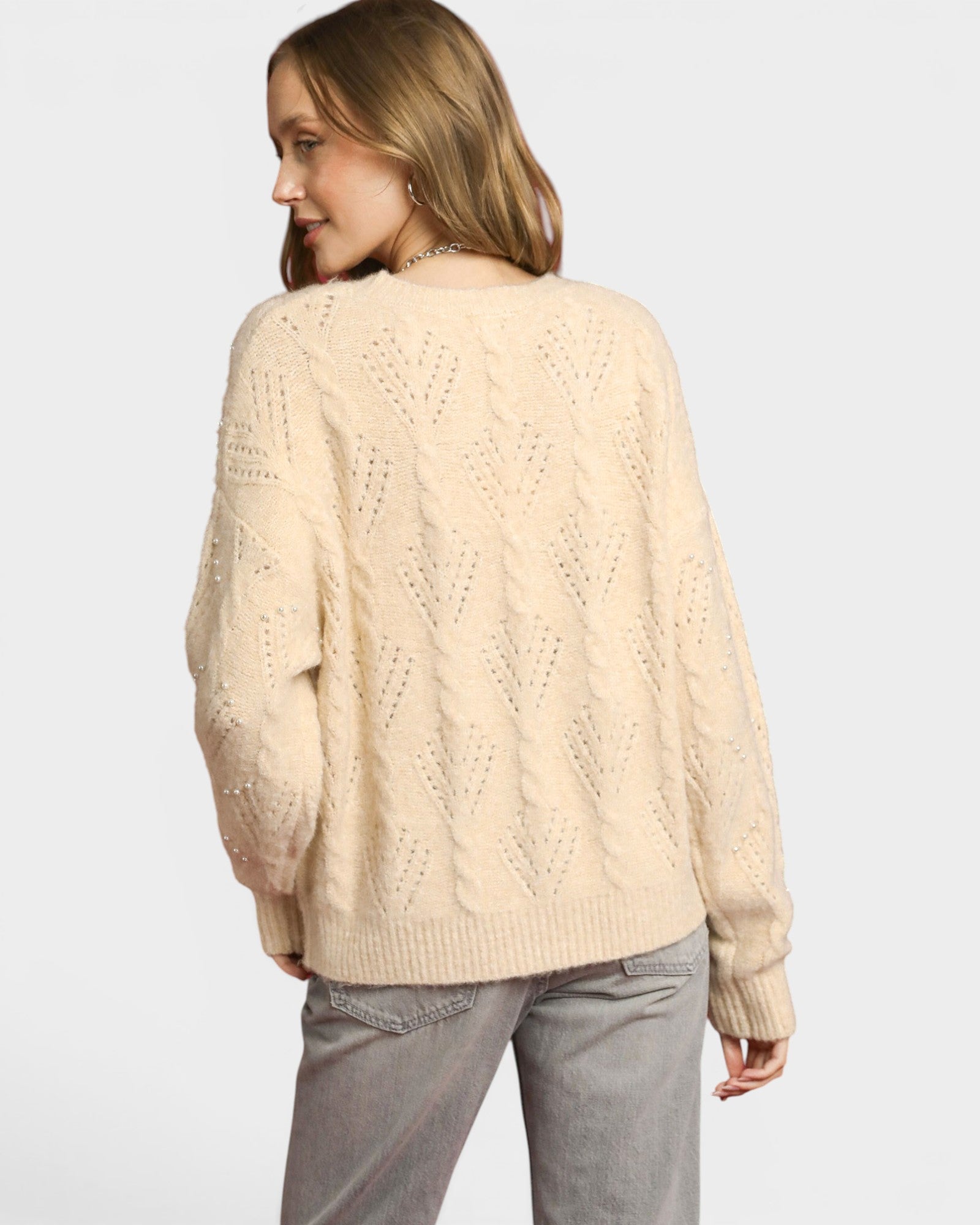Woman wearing a beige sweater on a light gray background
