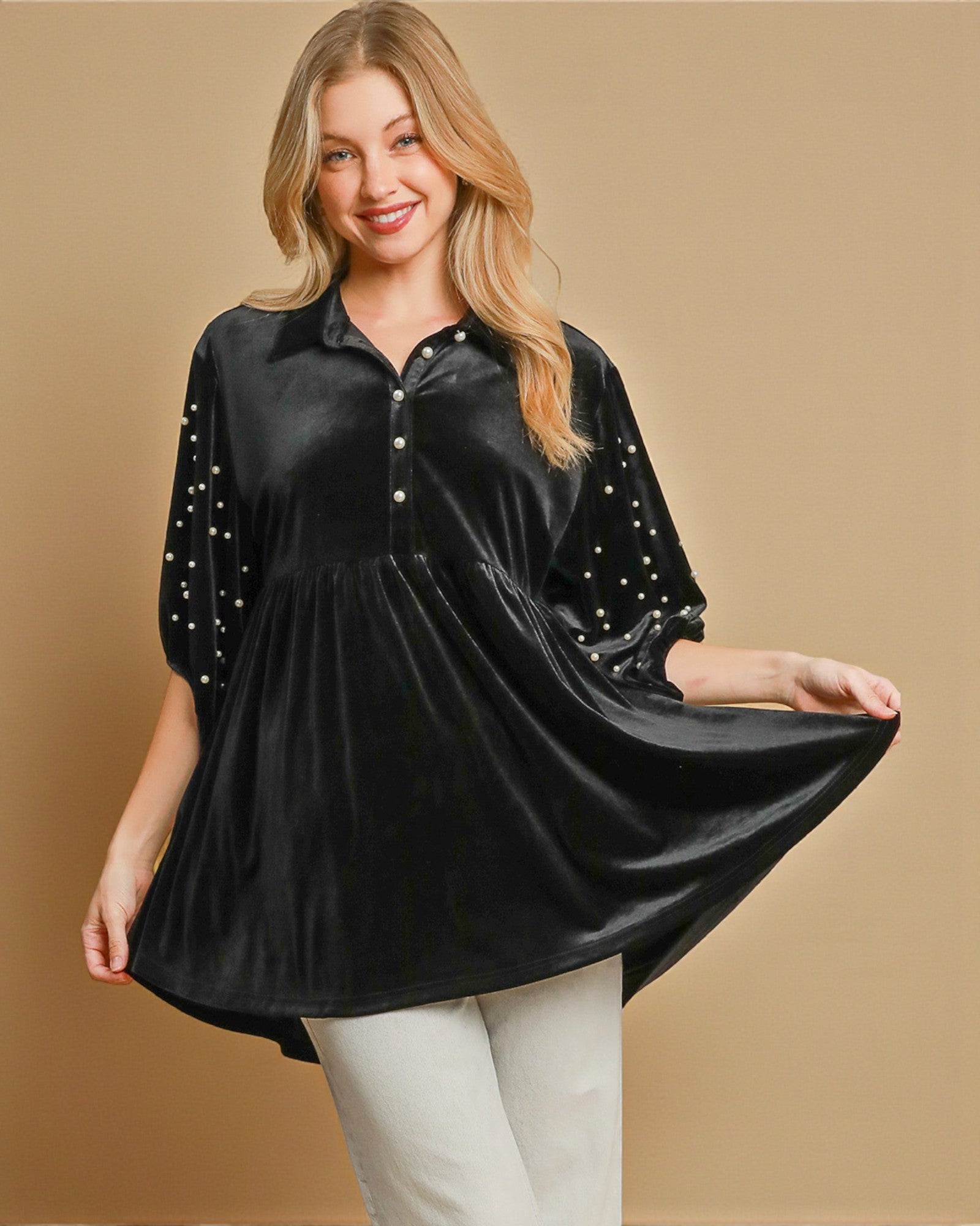 Woman wearing a black velvet blouse with star patterns on a beige background