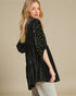 Woman wearing a black velvet kimono with pearl embellishments on a beige background