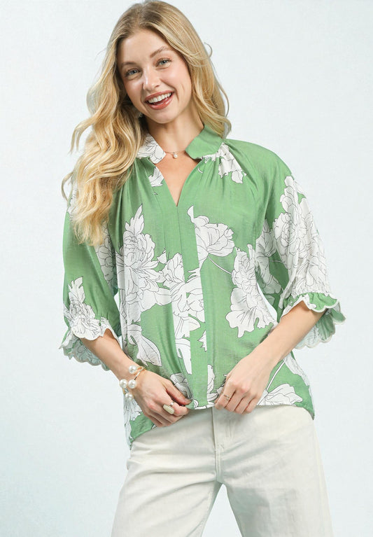 Woman wearing a green blouse with white floral patterns on a light gray background