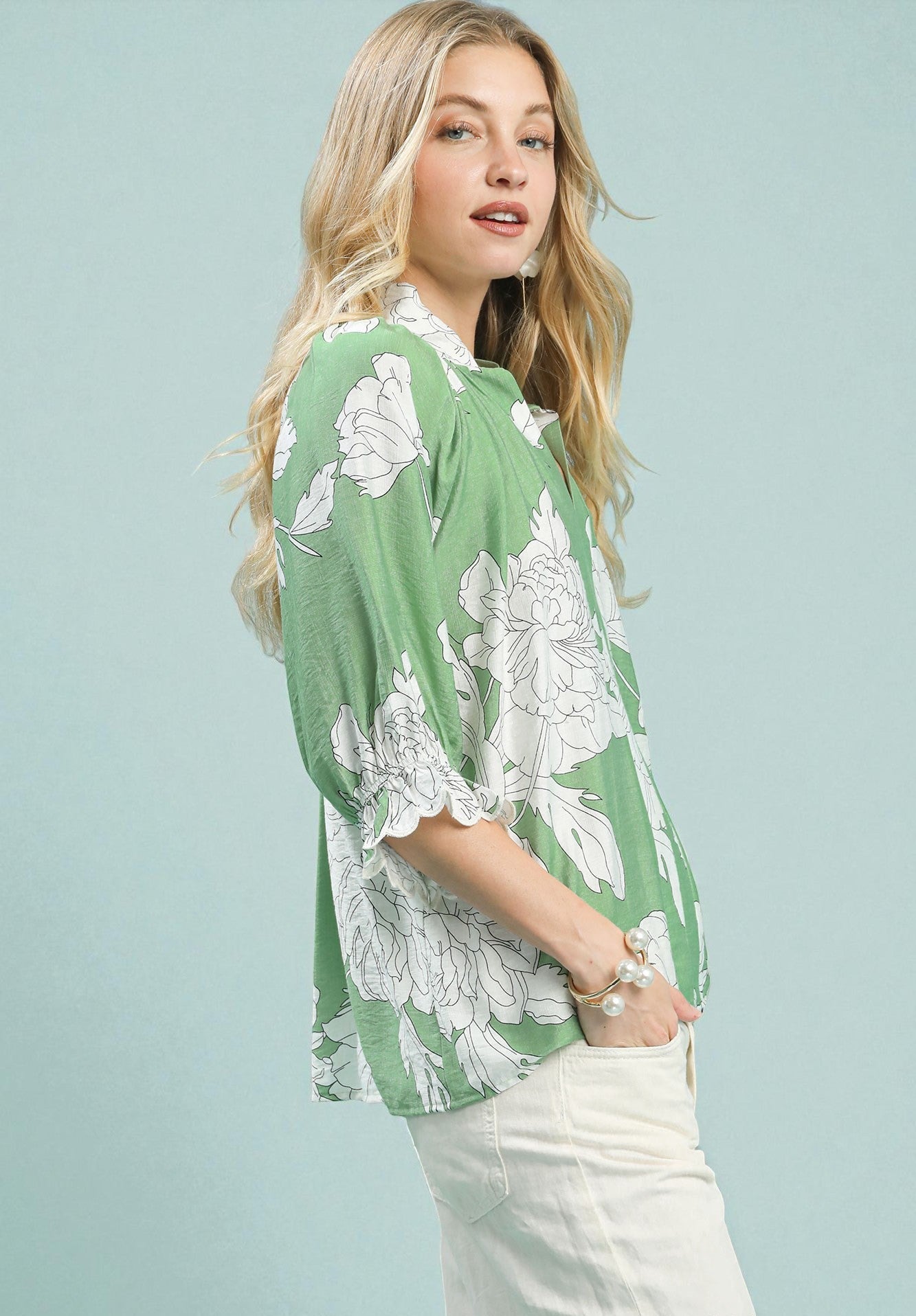 Woman wearing a green floral blouse against a light blue background