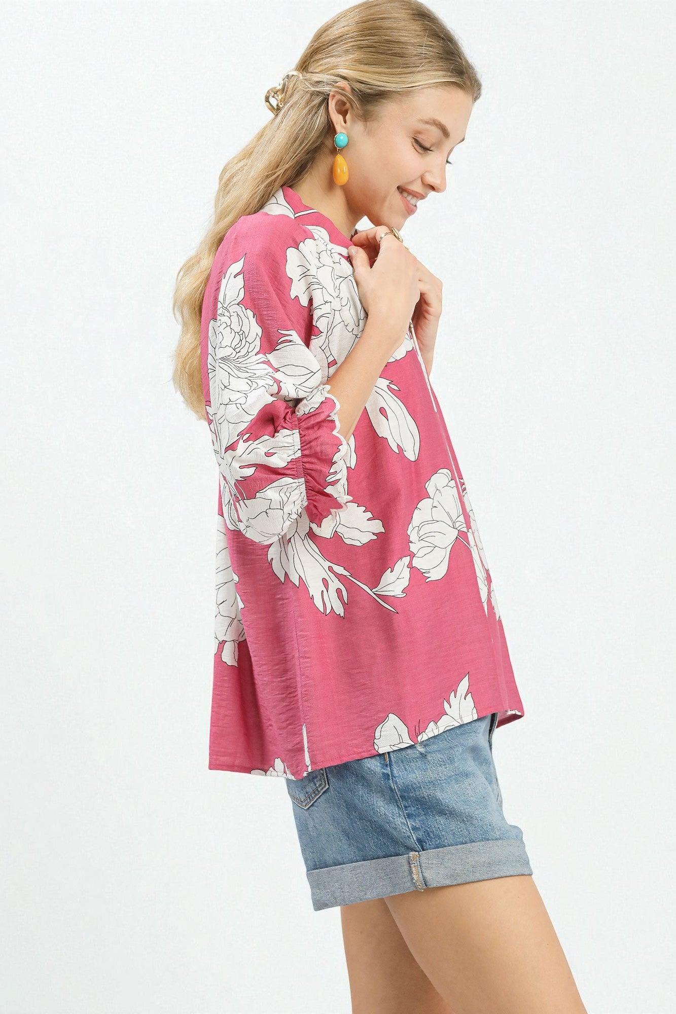 Woman wearing a pink floral blouse and denim shorts on a white background