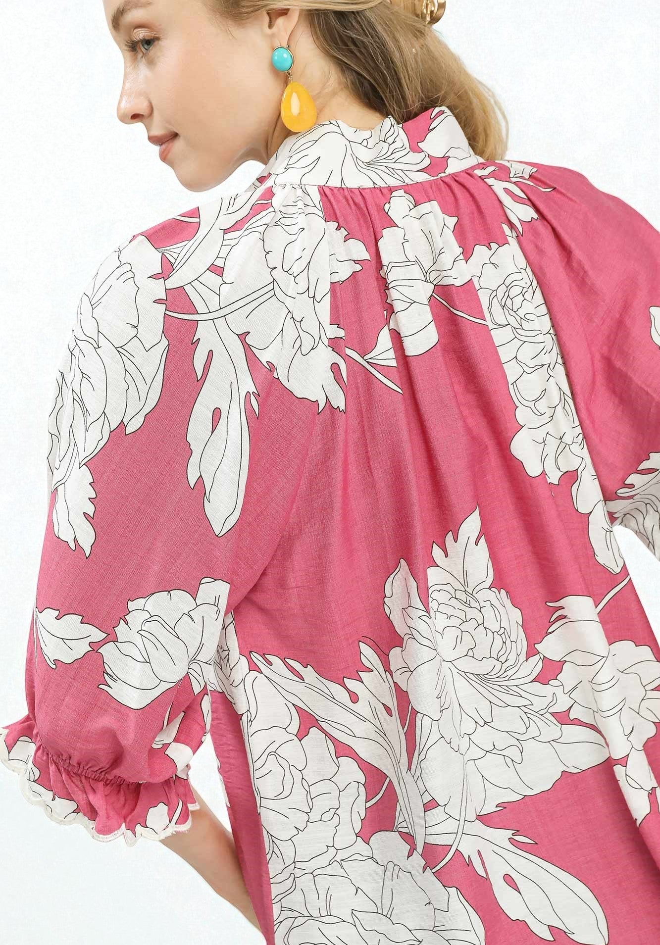 Person wearing a pink floral dress with white flowers on a white background