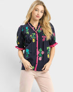 Woman wearing a black blouse with colorful floral embroidery on a white background