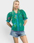 Woman wearing a green embroidered blouse with floral patterns on a white background