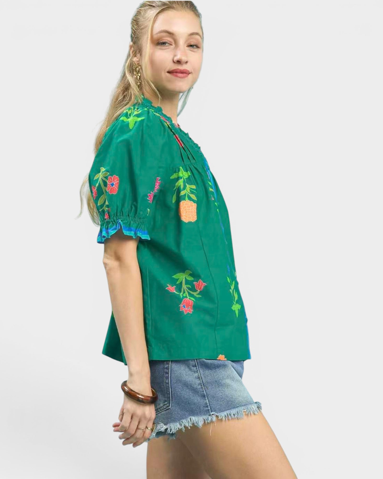 Woman wearing a green embroidered blouse with floral patterns on a white background