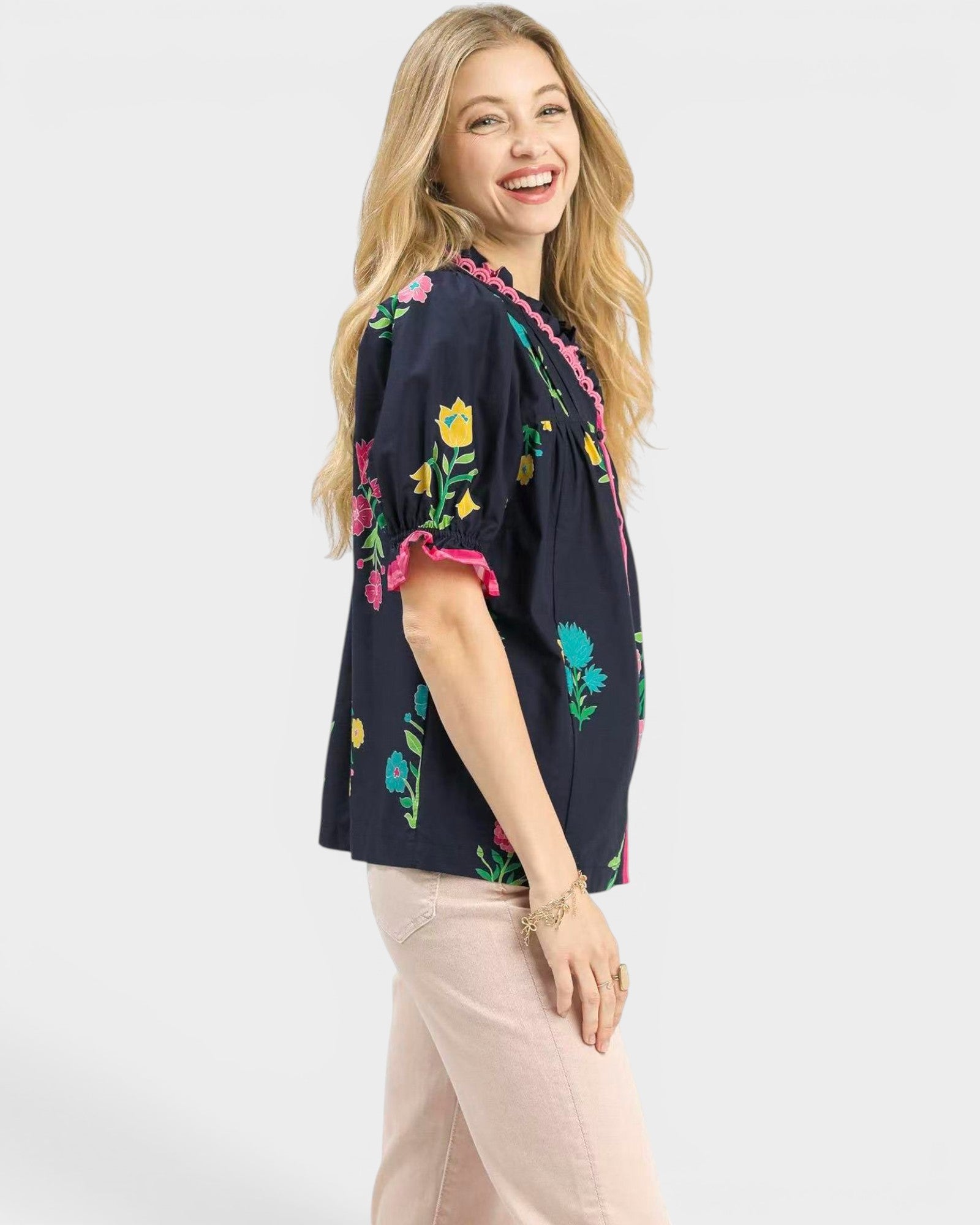 Woman wearing a navy blouse with colorful floral embroidery on a white background