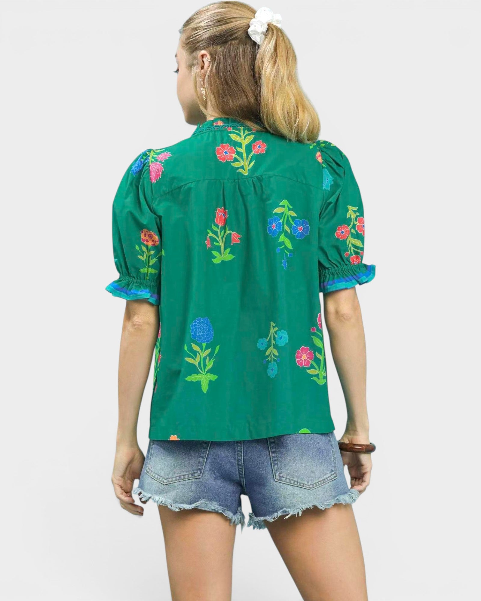 Woman wearing a green embroidered blouse with floral patterns on a white background