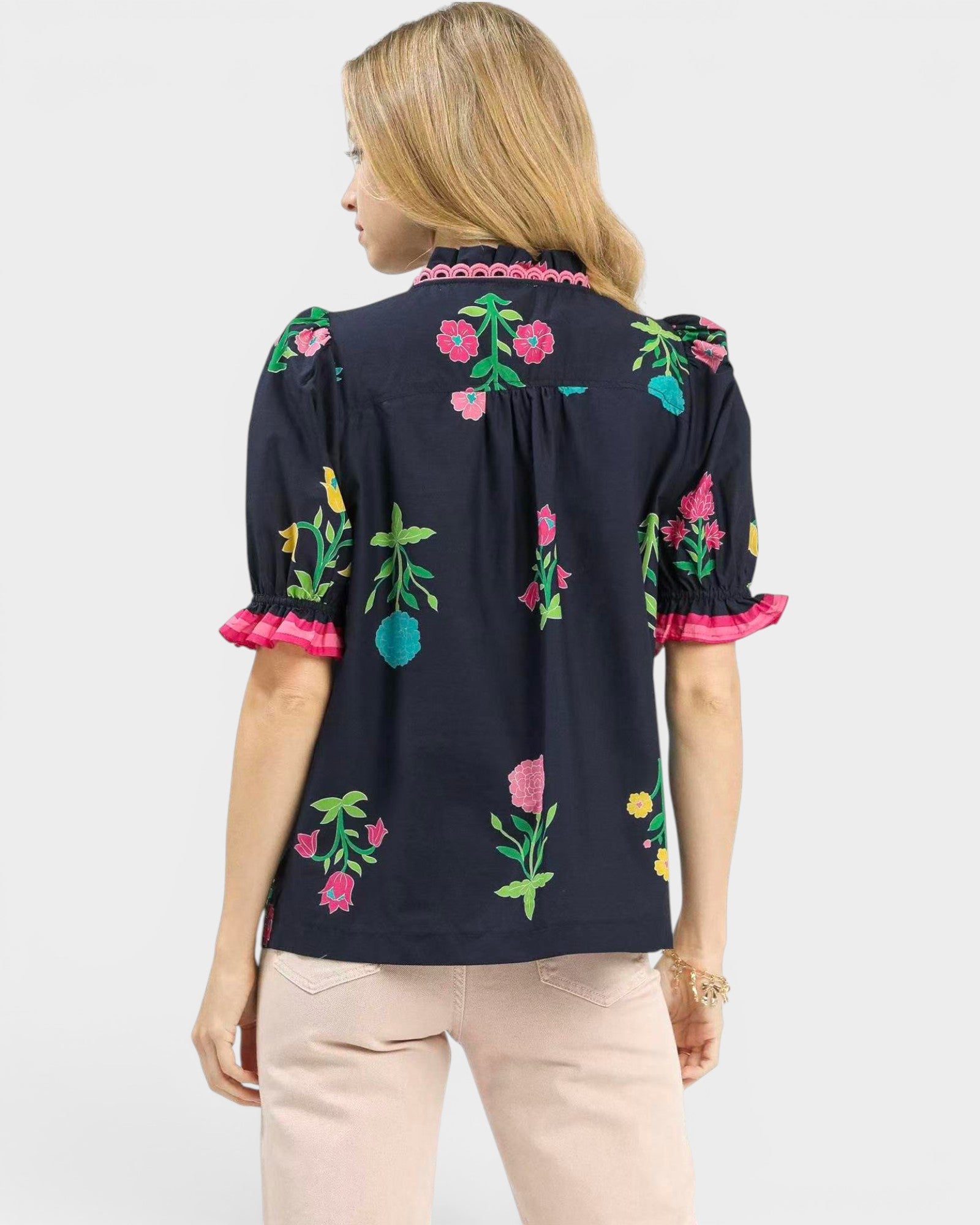 Woman wearing a black blouse with colorful floral embroidery on a white background