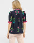 Woman wearing a black blouse with colorful floral embroidery on a white background