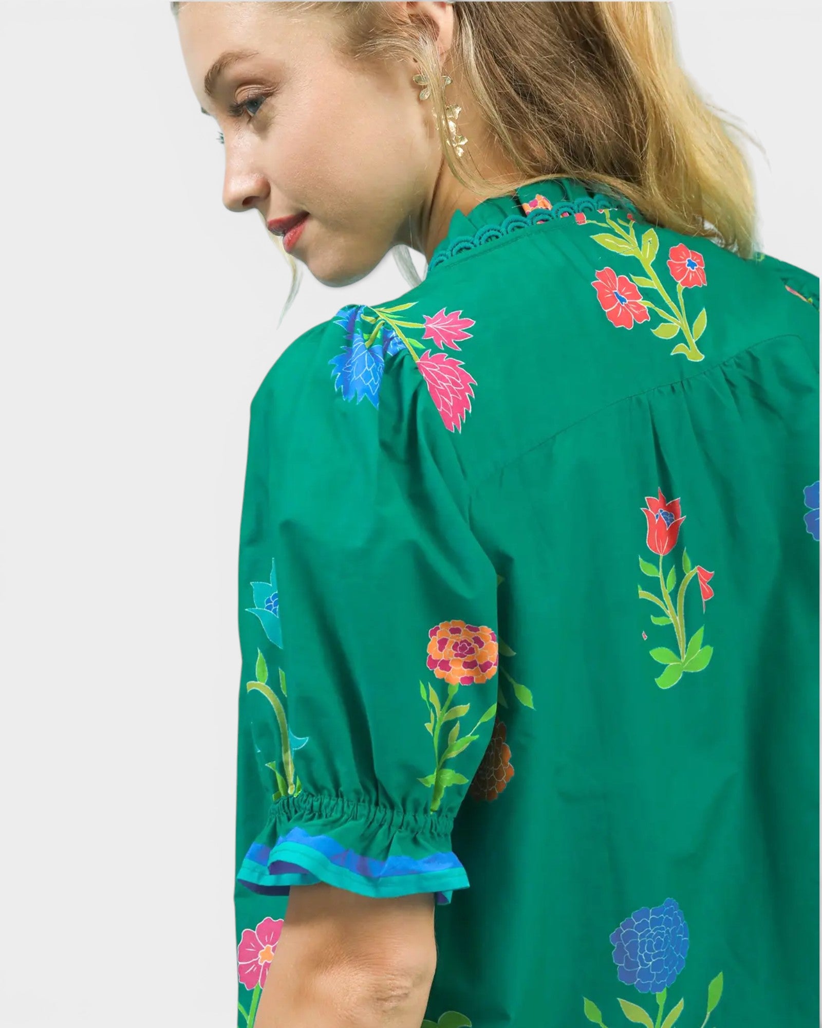Green blouse with colorful floral embroidery on a plain background