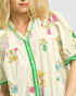 Woman wearing a floral blouse with green accents on a plain background