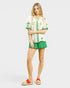 Woman wearing a floral blouse and green shorts on a white background