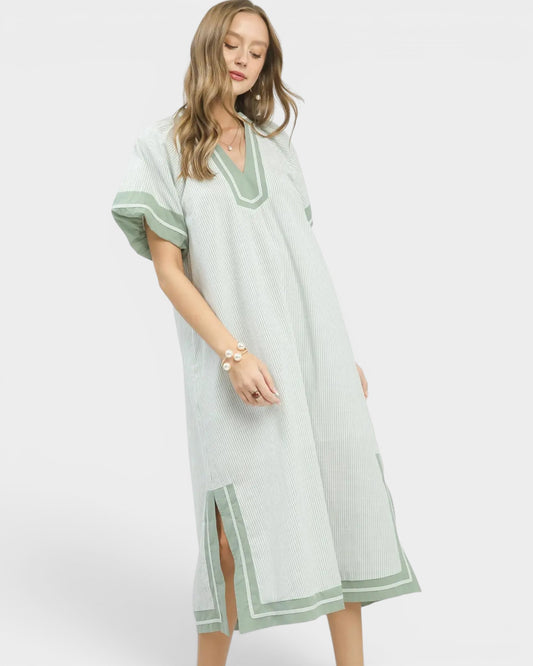 Woman wearing a light green dress with green trim on a white background