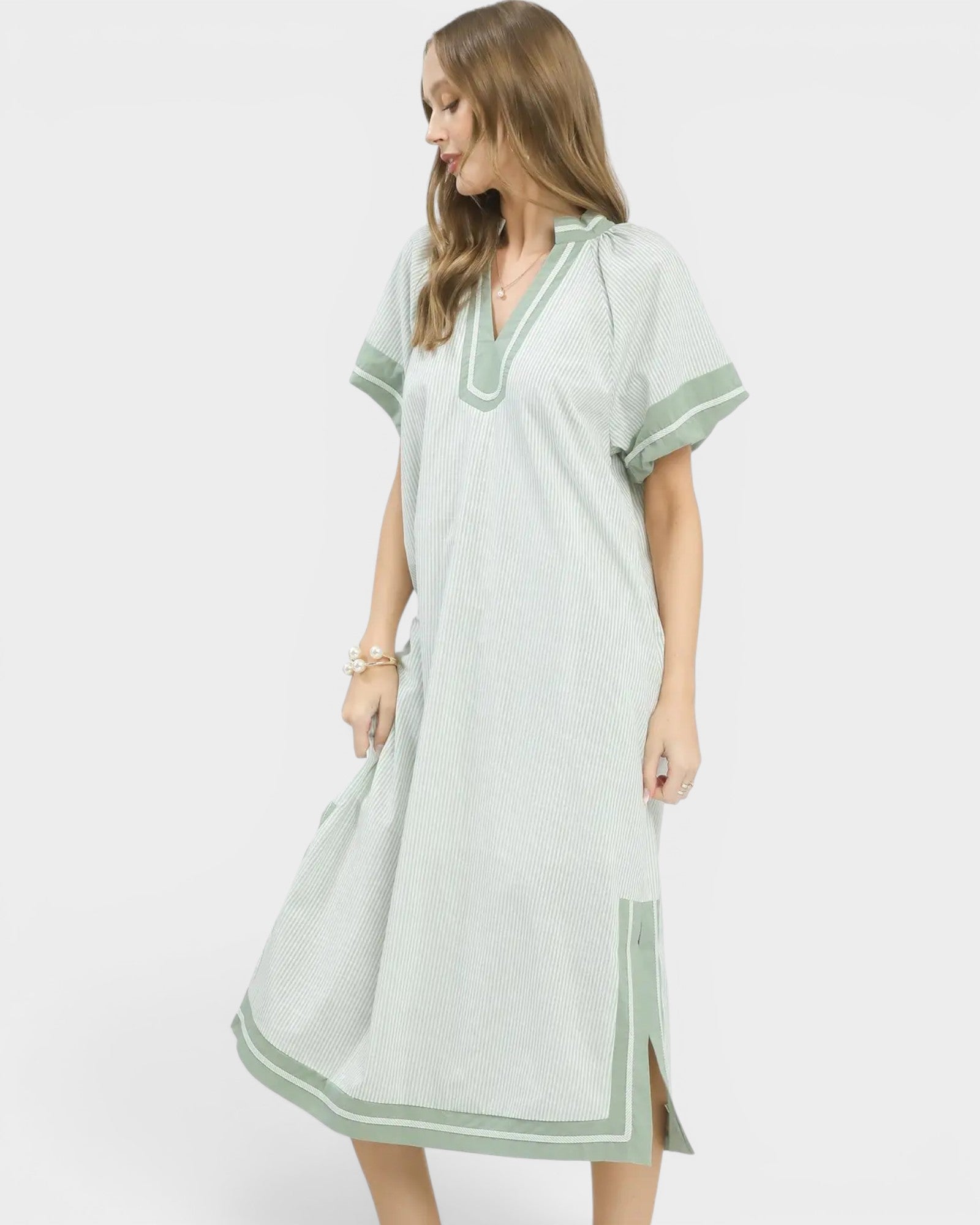 Woman wearing a light green dress with white trim on a white background