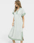 Woman wearing a light green dress with white trim on a white background