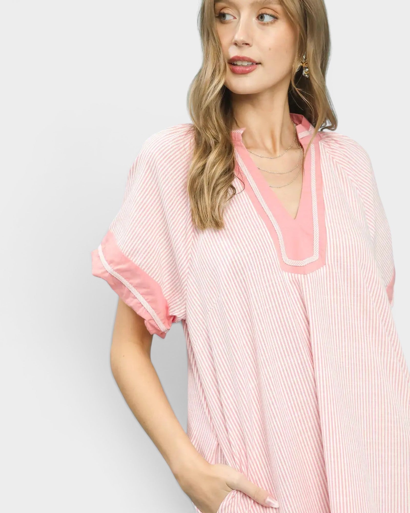 Woman wearing a pink and white striped dress with a plain background