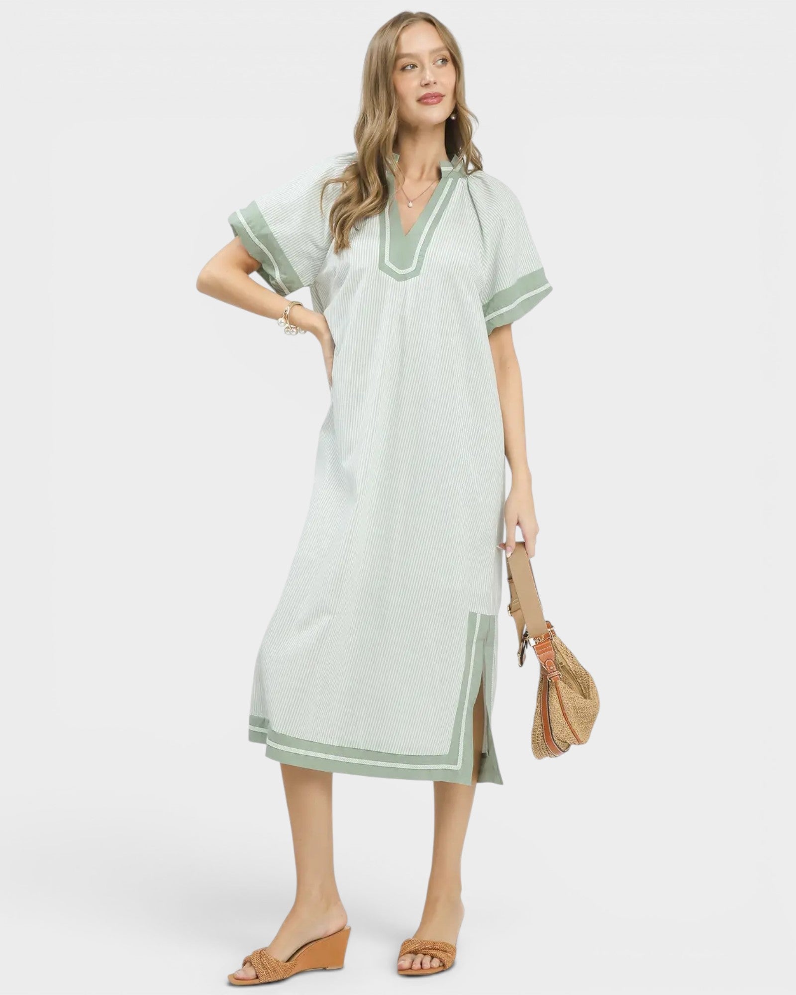 Woman wearing a light green dress with white trim on a white background