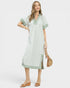 Woman wearing a light green dress with white trim on a white background