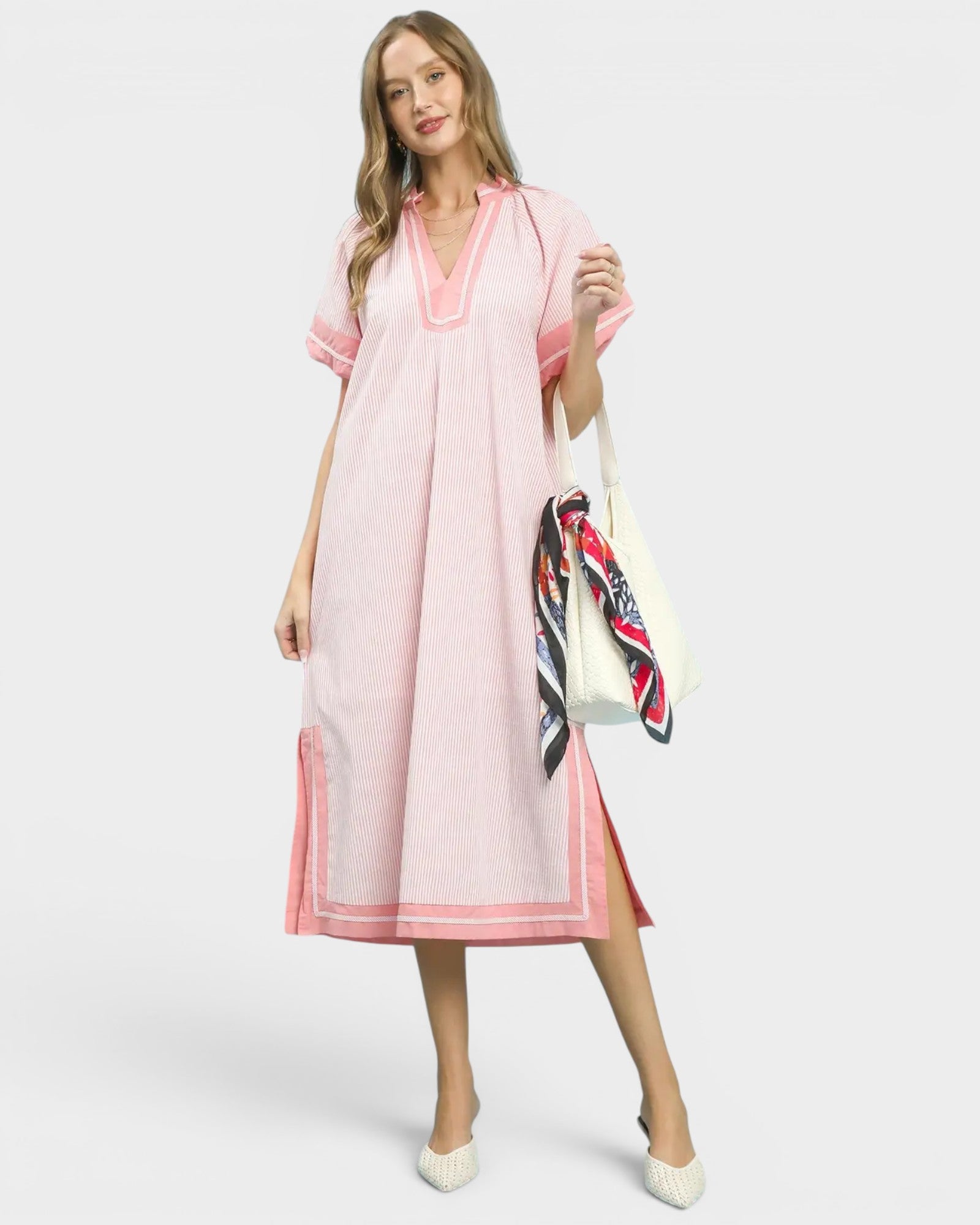 Woman wearing a pink dress holding a colorful scarf on a white background