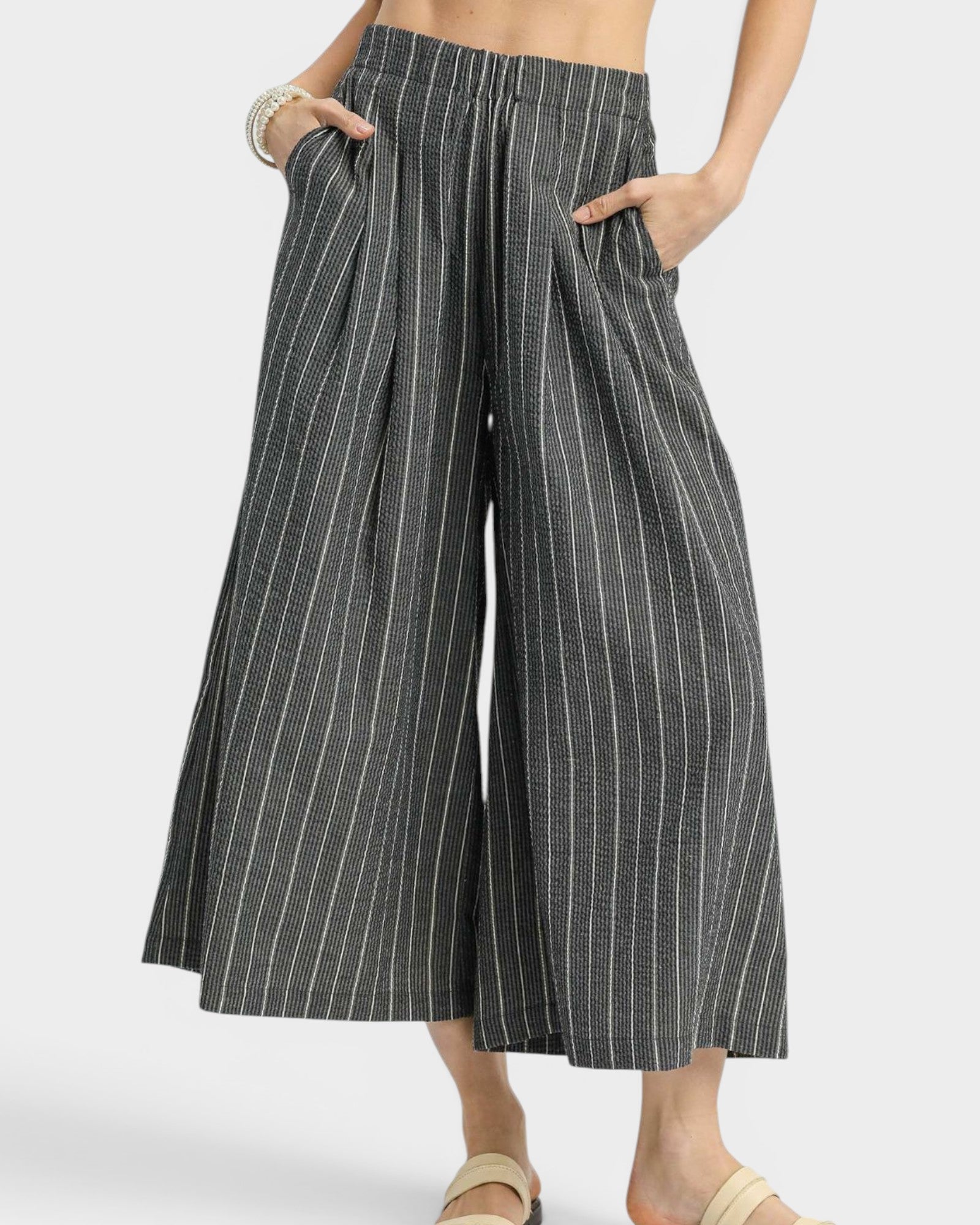 Person wearing black and white striped wide-leg pants on a light gray background