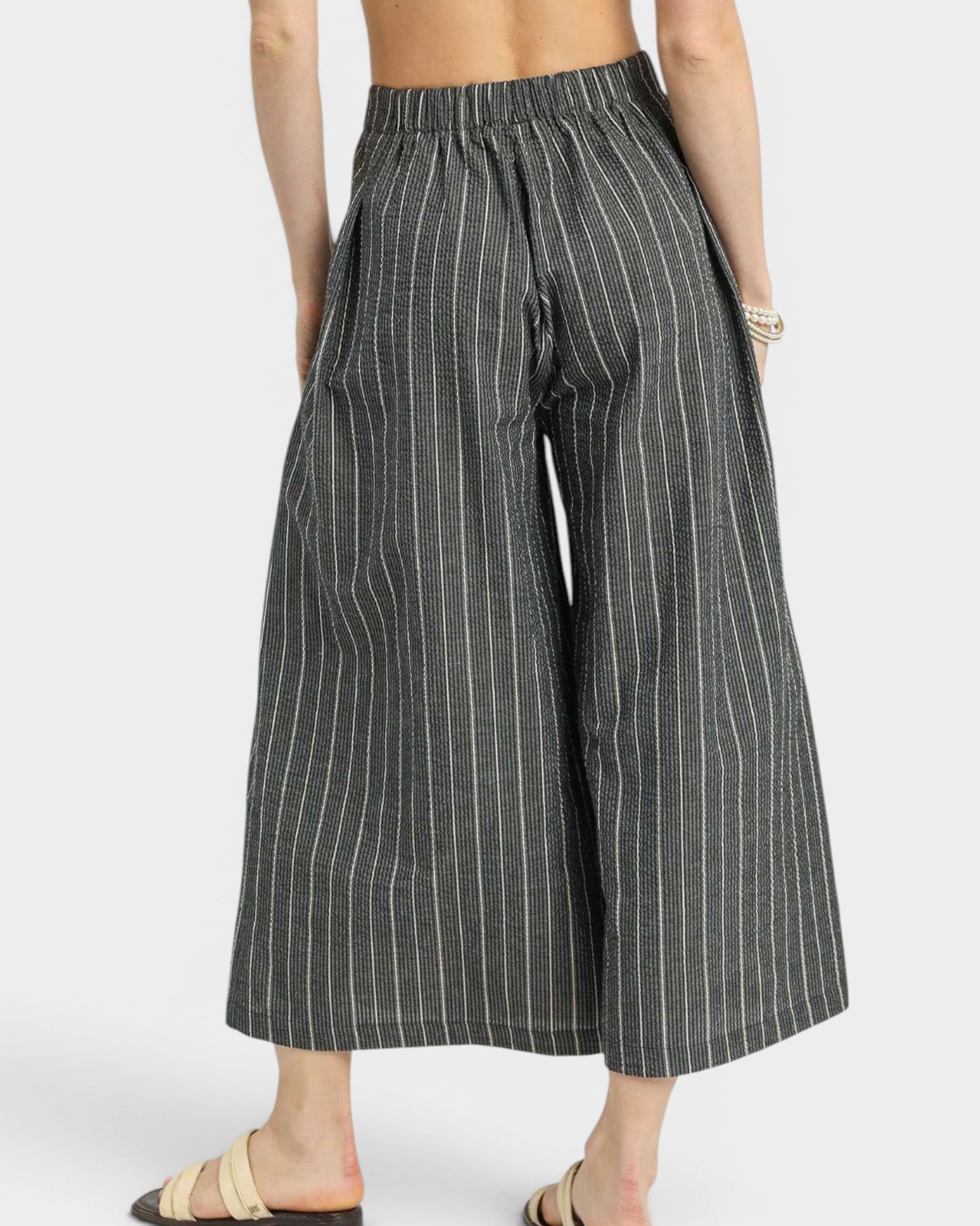 Person wearing black and white striped wide-leg pants on a white background