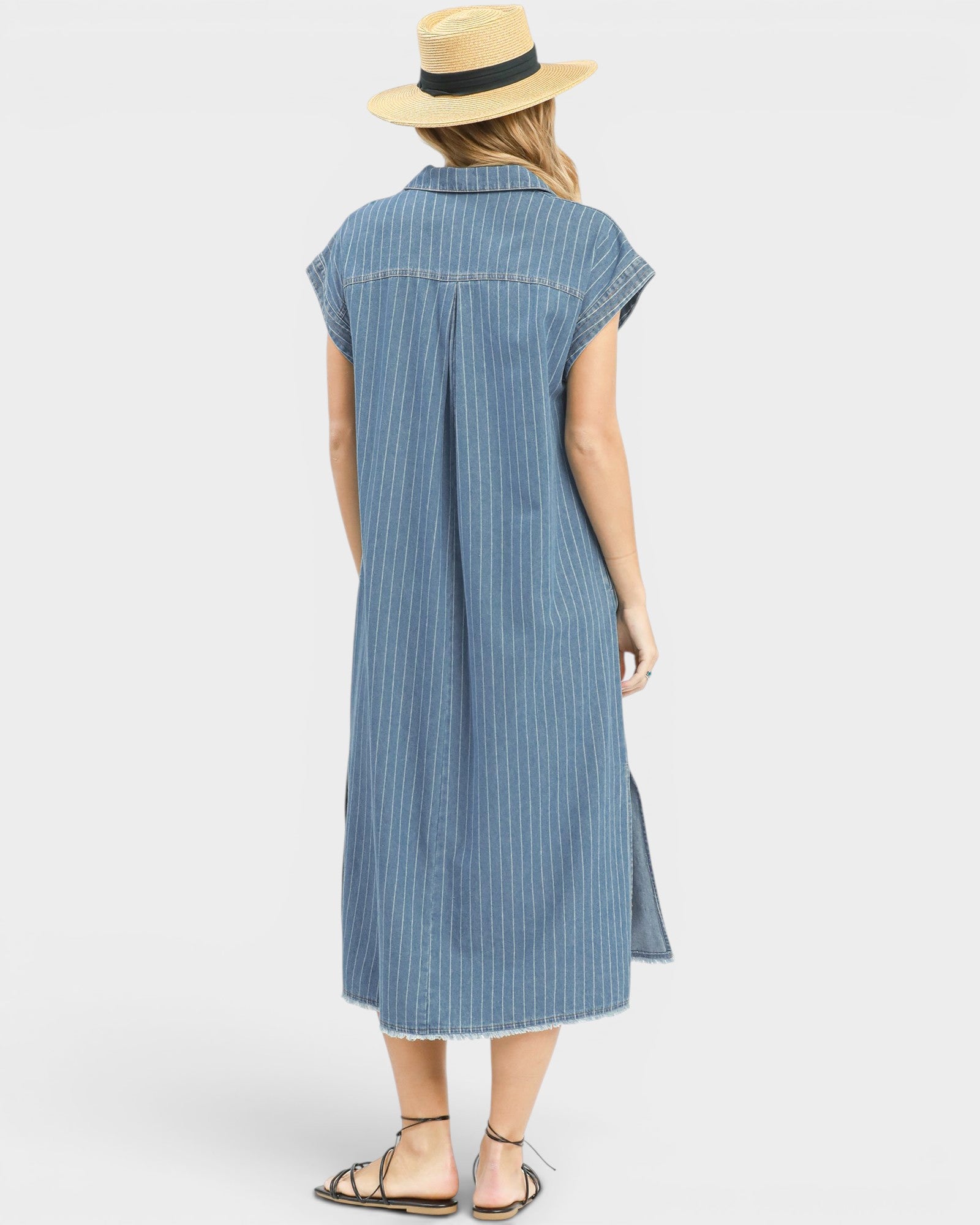 Woman wearing a blue striped dress and straw hat on a white background