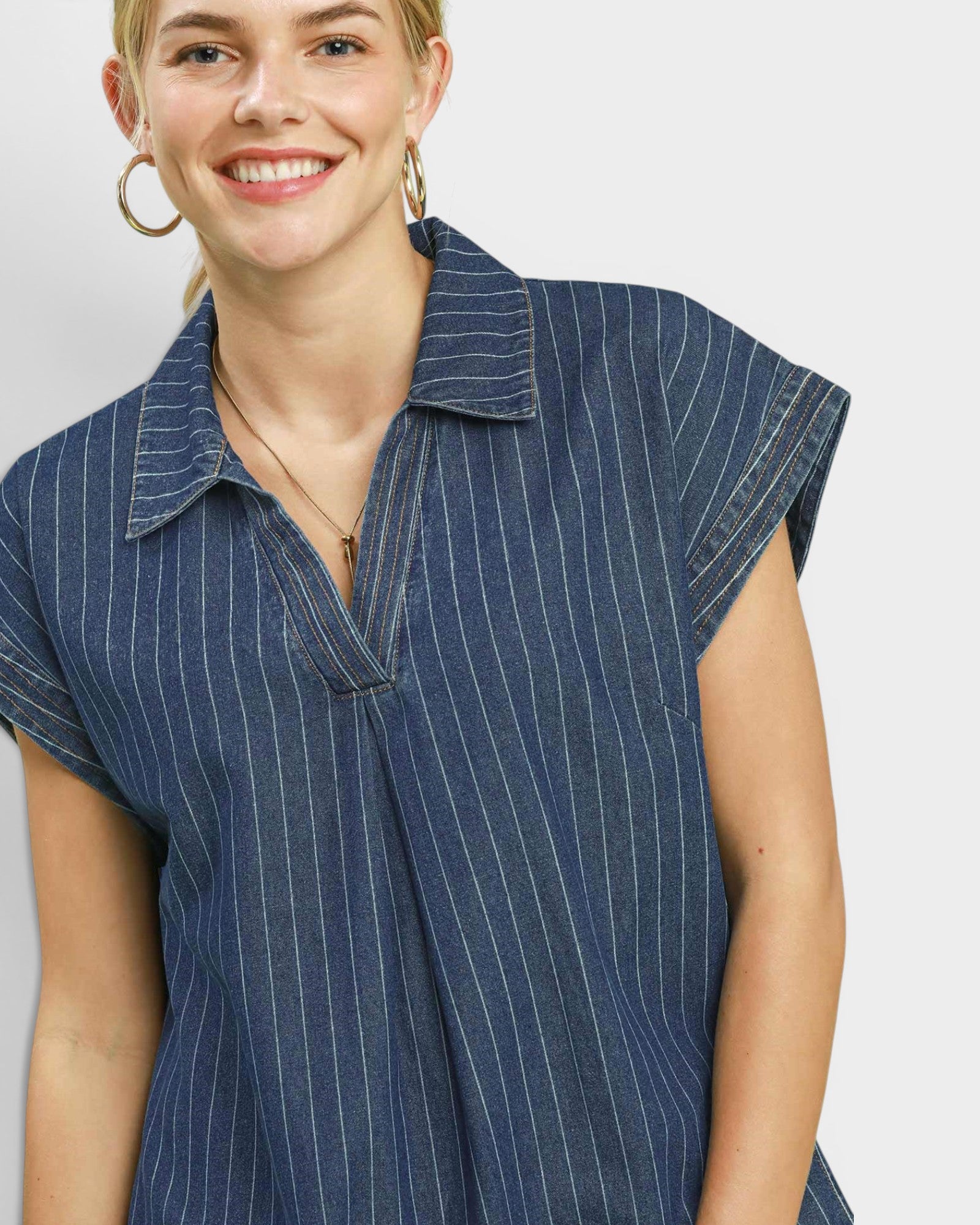 Woman wearing a blue pinstripe shirt against a plain background