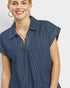 Woman wearing a blue pinstripe shirt against a plain background