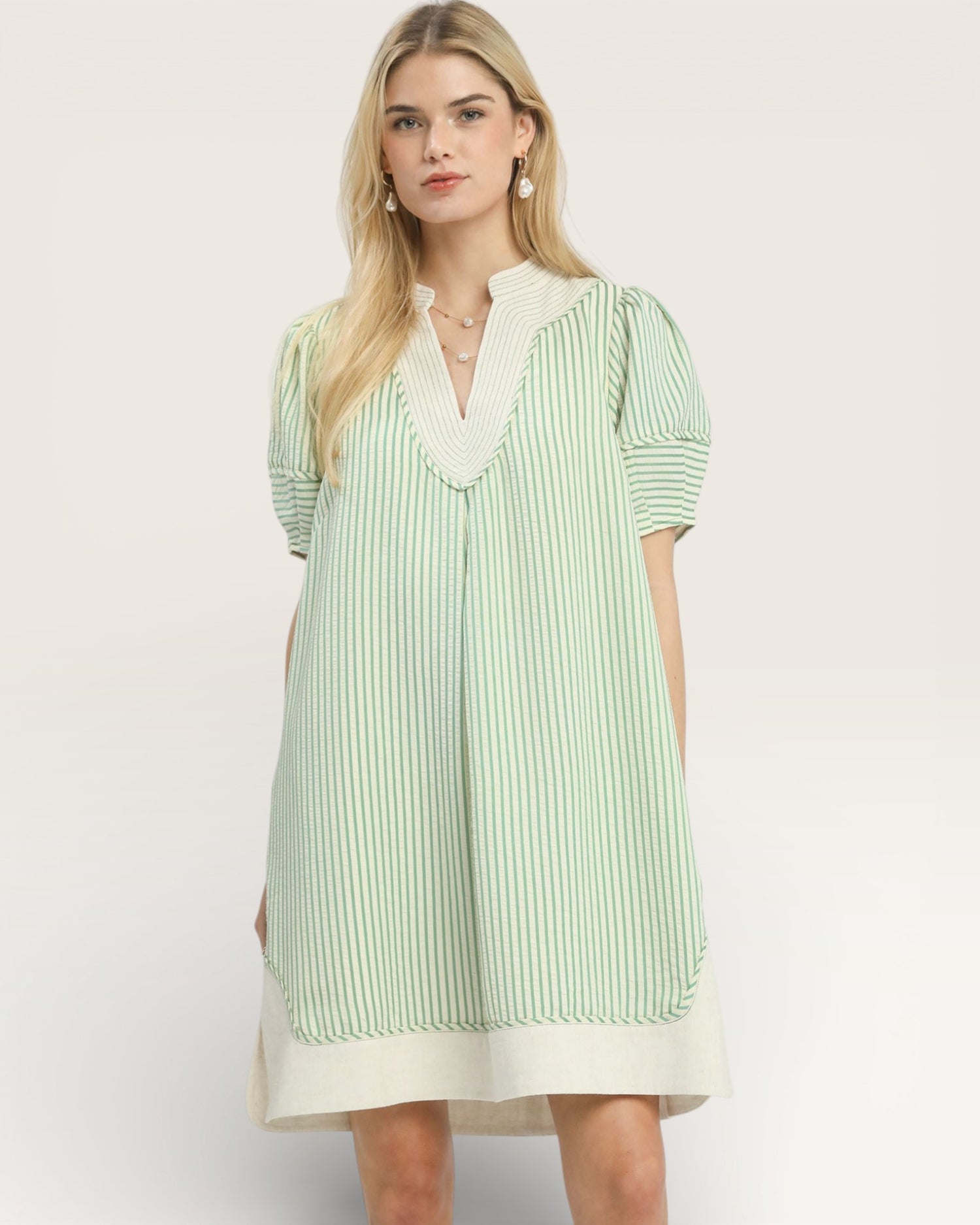 Woman wearing a green and white striped dress on a plain background