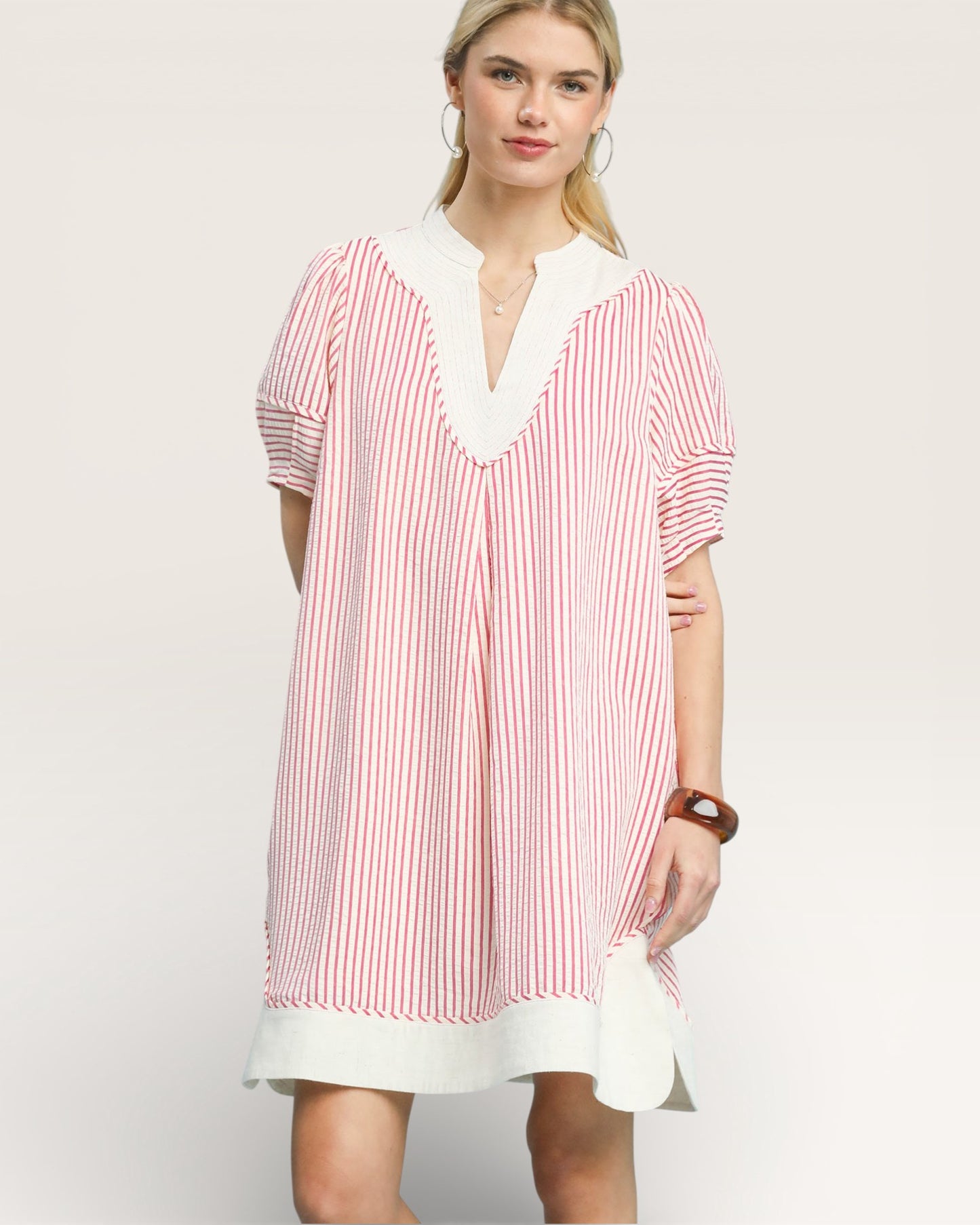 Woman wearing a red and white striped dress with a white collar on a light background