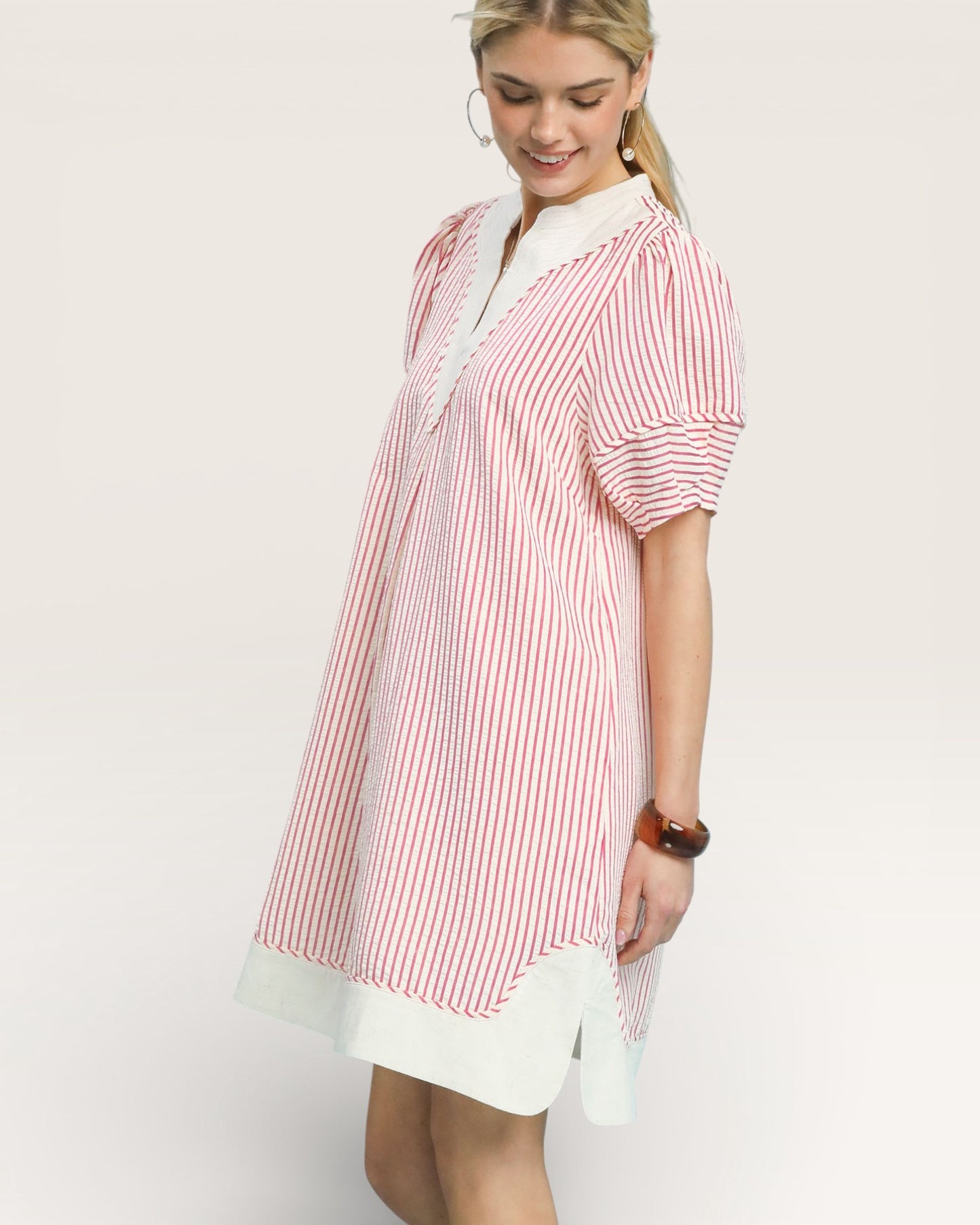 Woman wearing a red and white striped shirt with a white skirt on a light background