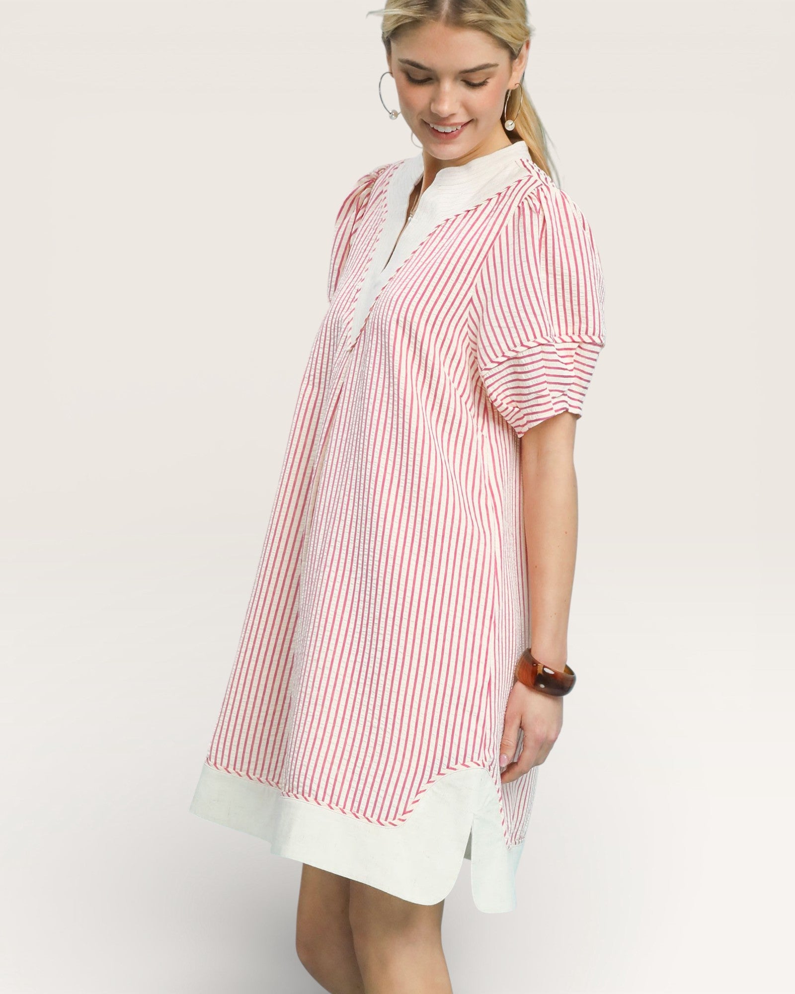 Woman wearing a red and white striped shirt with a white skirt on a light background