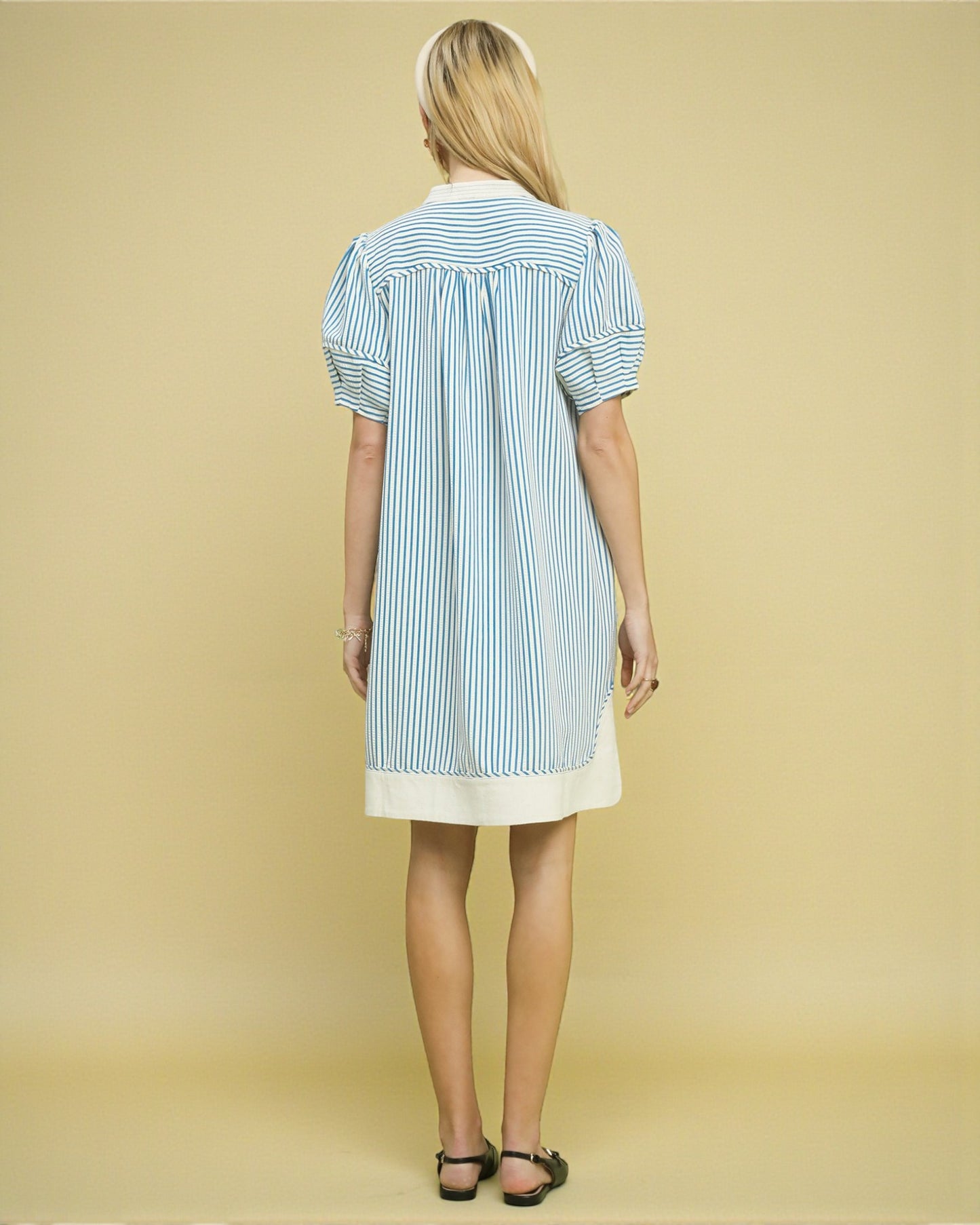 Woman wearing a blue and white striped dress on a beige background