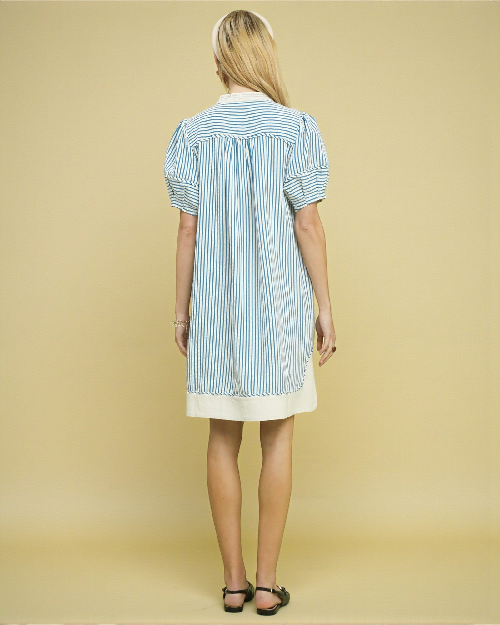 Woman wearing a blue and white striped dress on a beige background