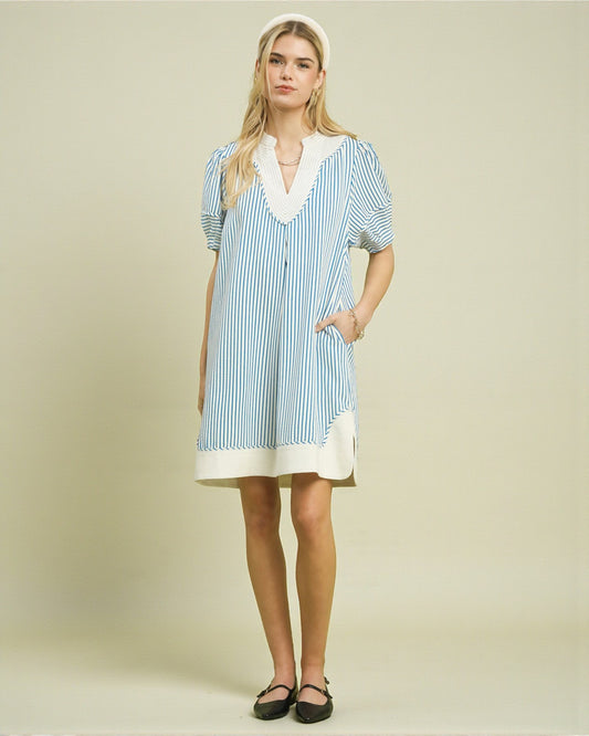 Woman wearing a blue and white striped dress with a plain background