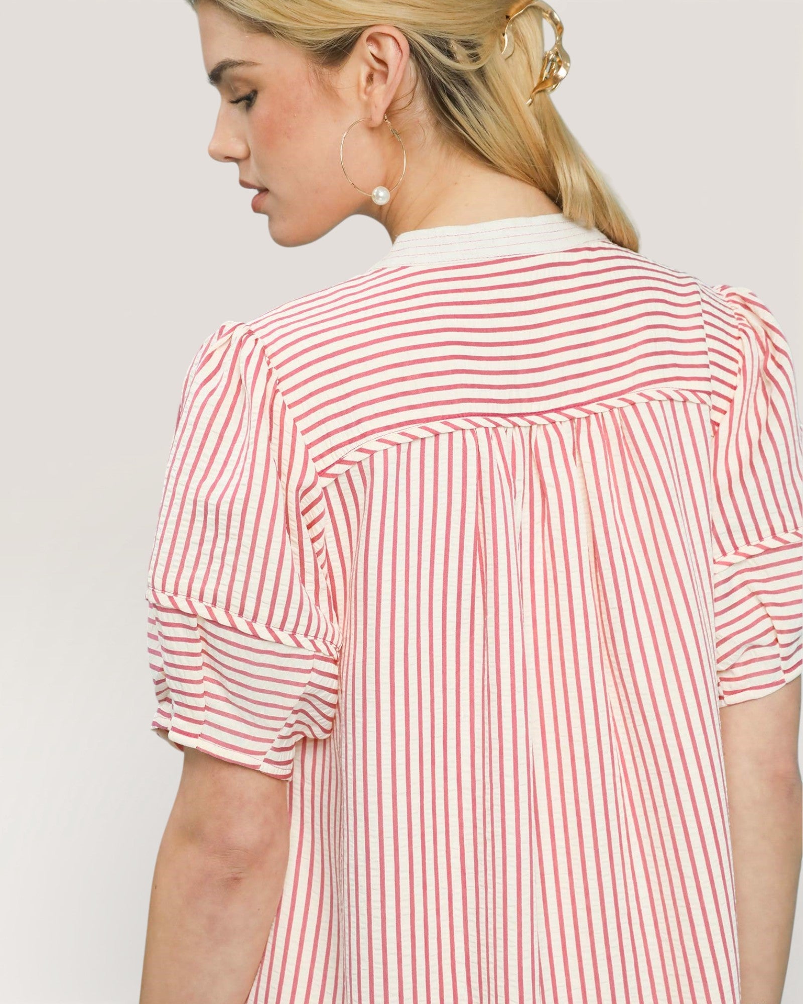 Woman wearing a red and white striped shirt against a plain background