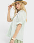 Woman wearing a light green striped blouse and a straw hat on a white background