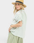 Woman wearing a light green blouse and beige hat on a white background