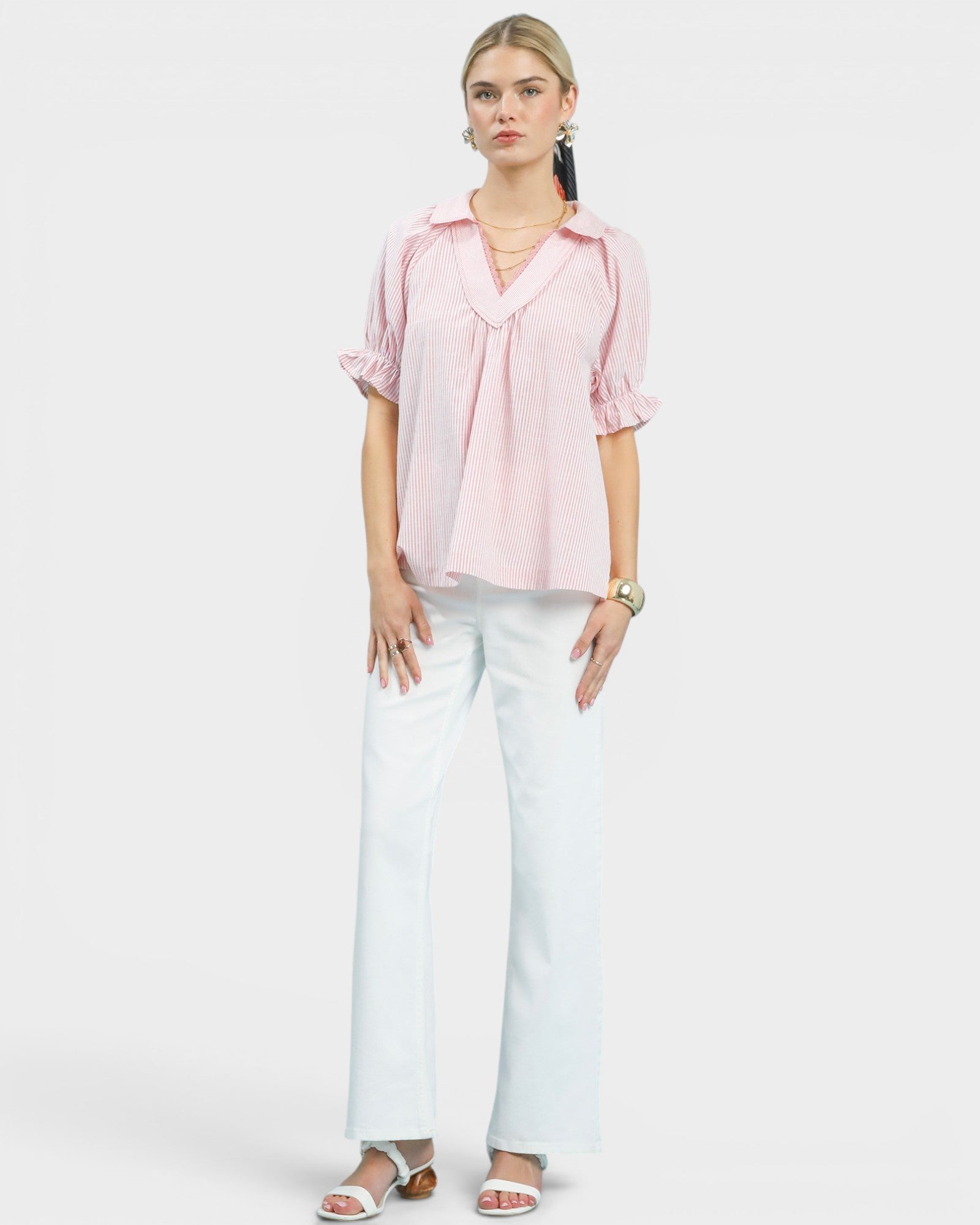 Woman wearing a pink blouse and white pants on a white background