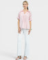 Woman wearing a pink blouse and white pants on a white background