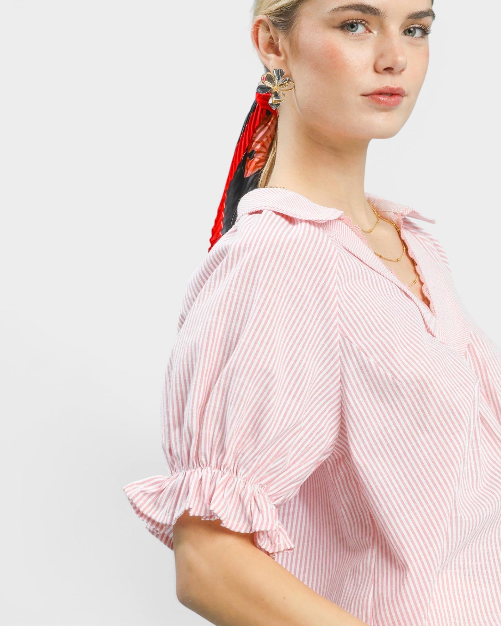 Woman wearing a pink striped blouse with a plain background