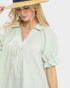 Woman wearing a light green striped shirt with a plain background