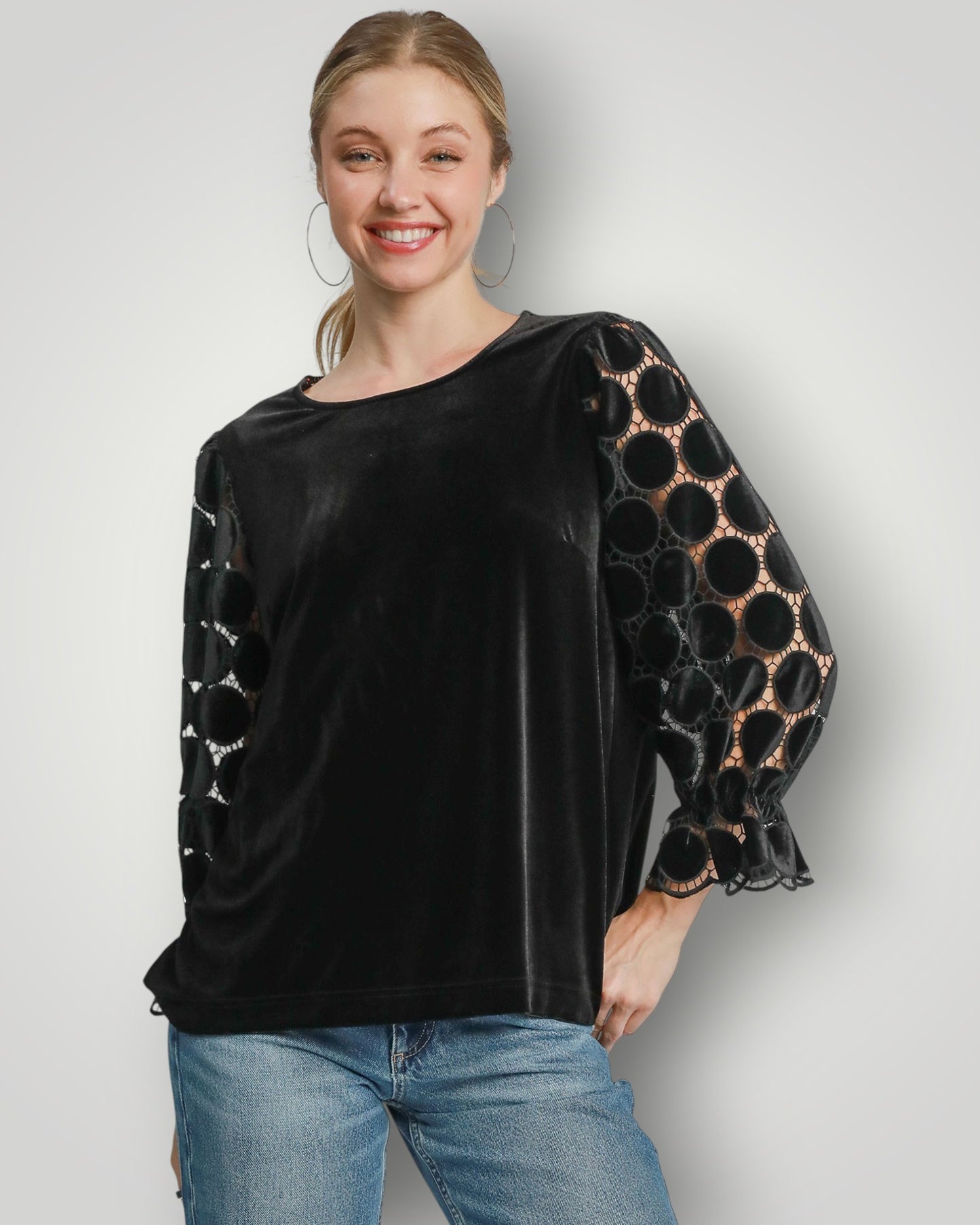 Woman wearing a black blouse with patterned sleeves on a plain background