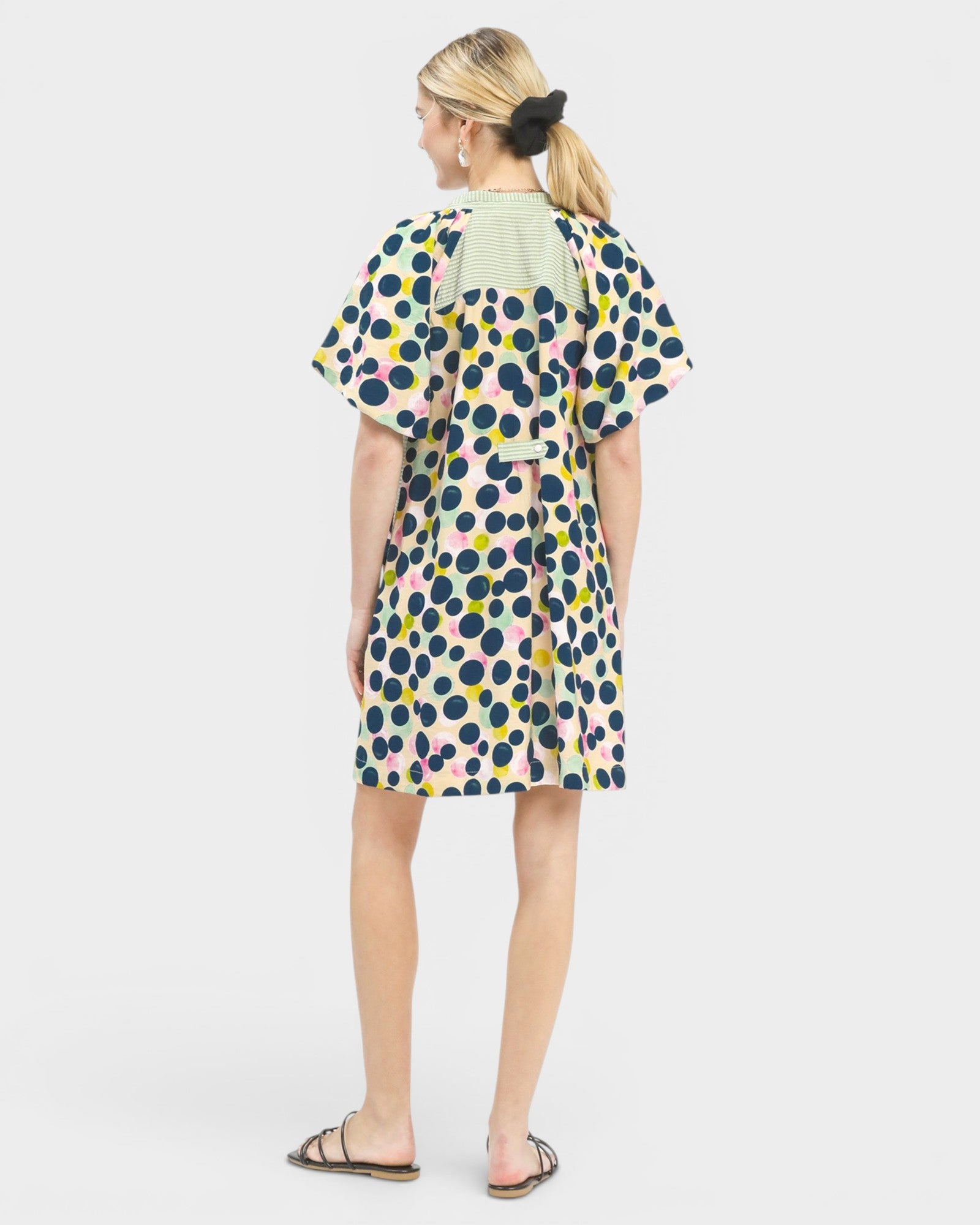 Woman wearing a colorful polka dot dress on a white background