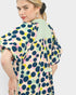 Woman wearing a colorful polka dot dress with a light green collar on a white background